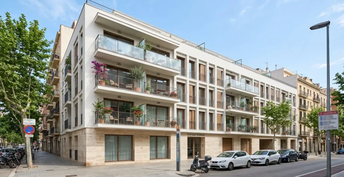 Vista en ángulo amplio de la fachada de un edificio residencial contemporáneo español con balcones en una calle urbana soleada